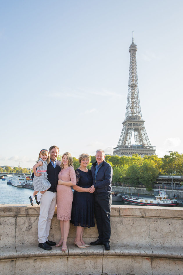 Family photo in Paris taken in front of the Eiffel Tower along the Seine.