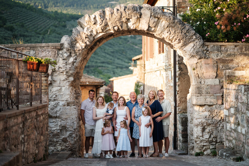 Our family photo standing under the arch in Spello, Italy on a cobblestone street.